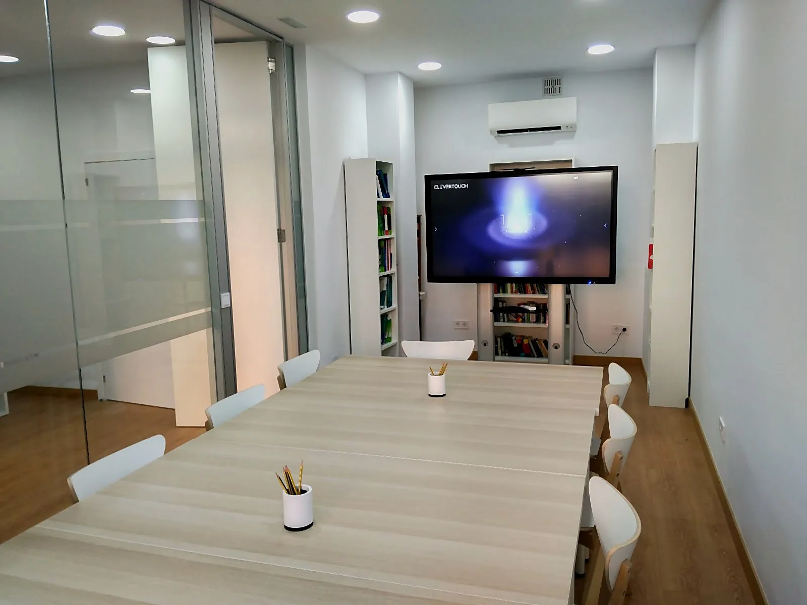 Aula principal de Aleza Idiomas con pantalla interactiva, mesa de trabajo y estanterías de libros